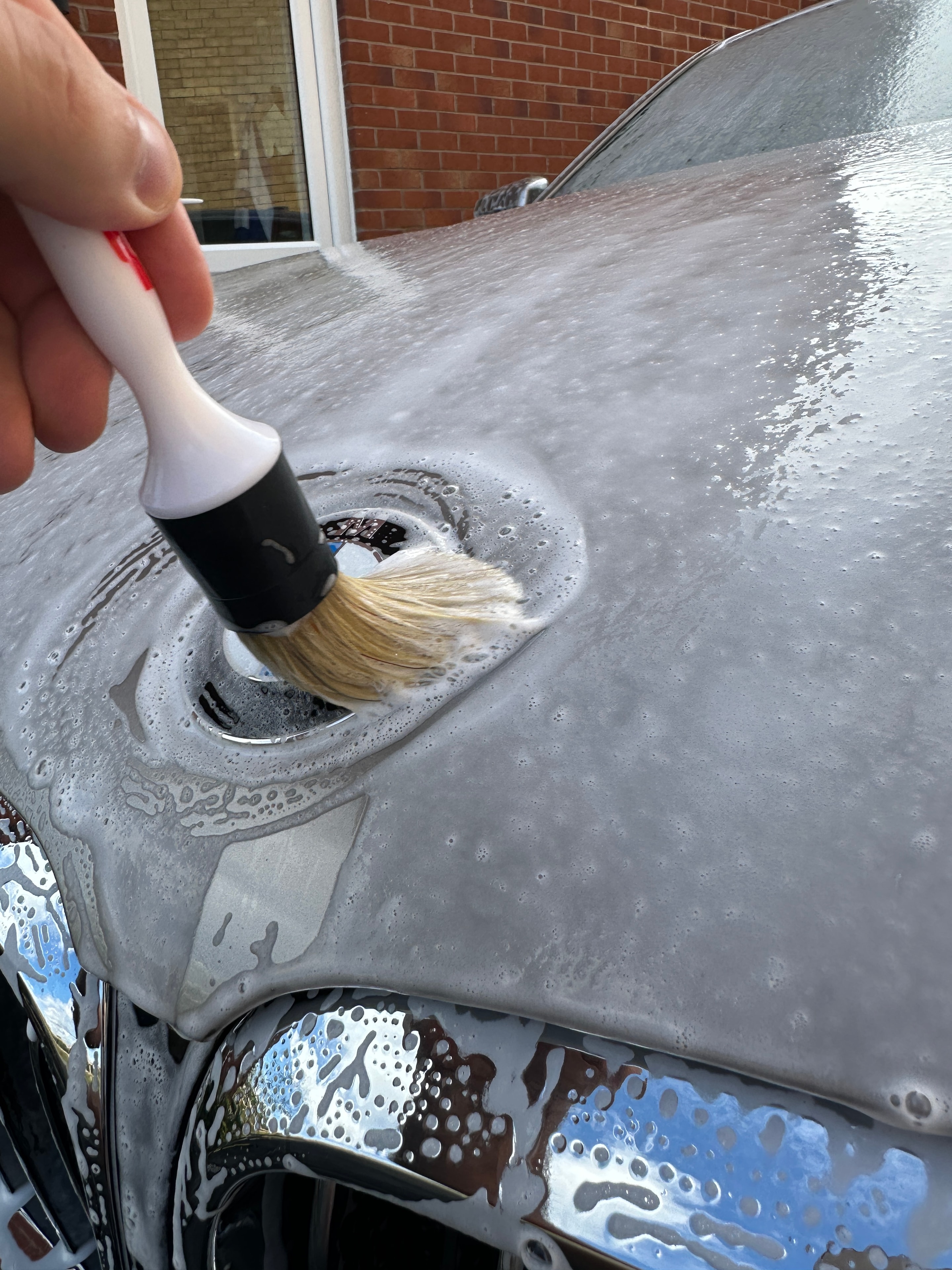 Detailing brush cleaning chrome trim with snow foam
